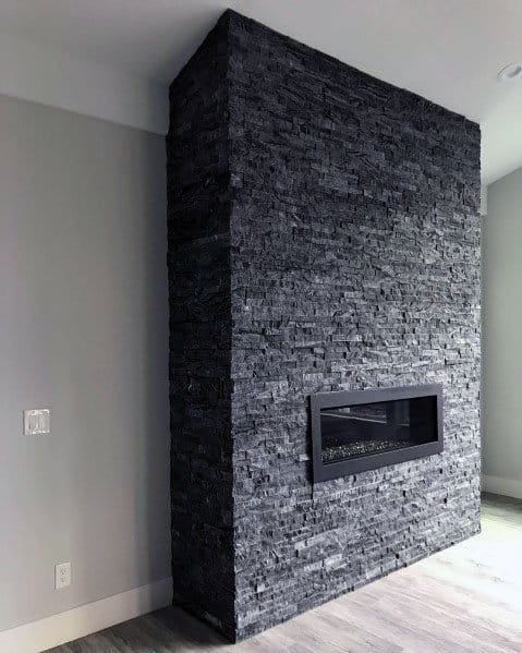 Bold dark grey stacked stone fireplace with a sleek rectangular insert for a modern minimalist look