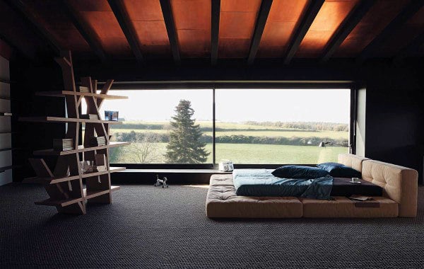 Minimalist bedroom with large window showing countryside view and floor mattress