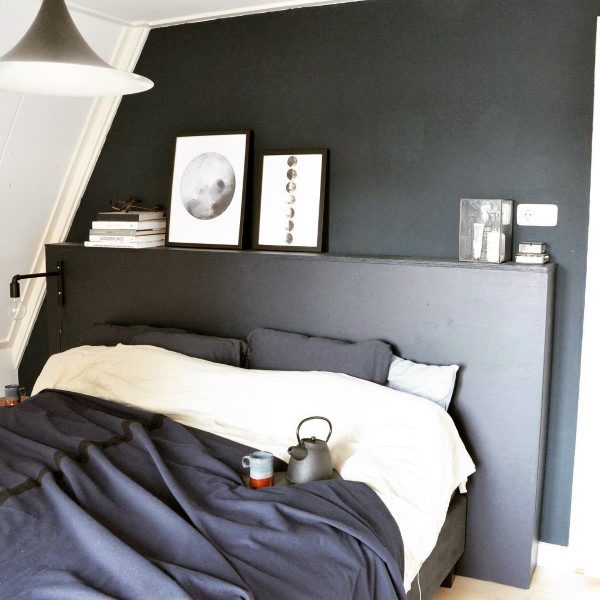Minimalist navy bedroom with moon-themed artwork, cozy bedding, and a sleek pendant light.