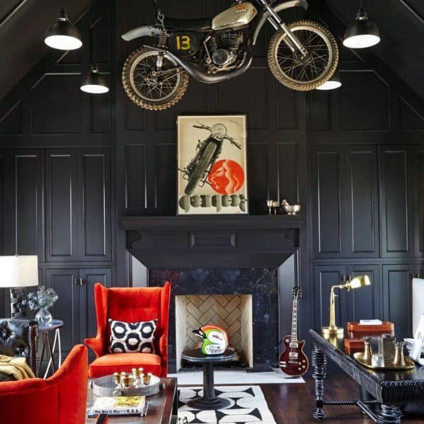 Stylish room with dark navy built-in shelves, a vintage motorcycle display, red armchairs, and a modern fireplace.