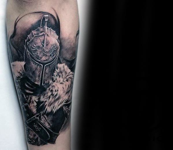 Realistic black and grey Dark Souls tattoo of a knight in detailed armor with fur cloak, covering the forearm.