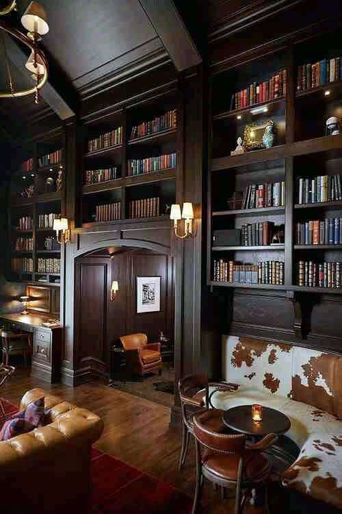Cozy library featuring tall wooden shelves, leather chairs, cowhide accents, and warm lighting