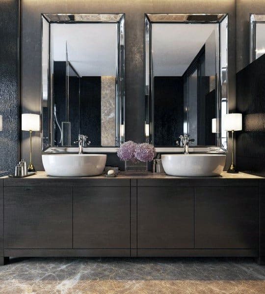 Modern double sink vanity with dark wood and large mirrors in luxury bathroom.