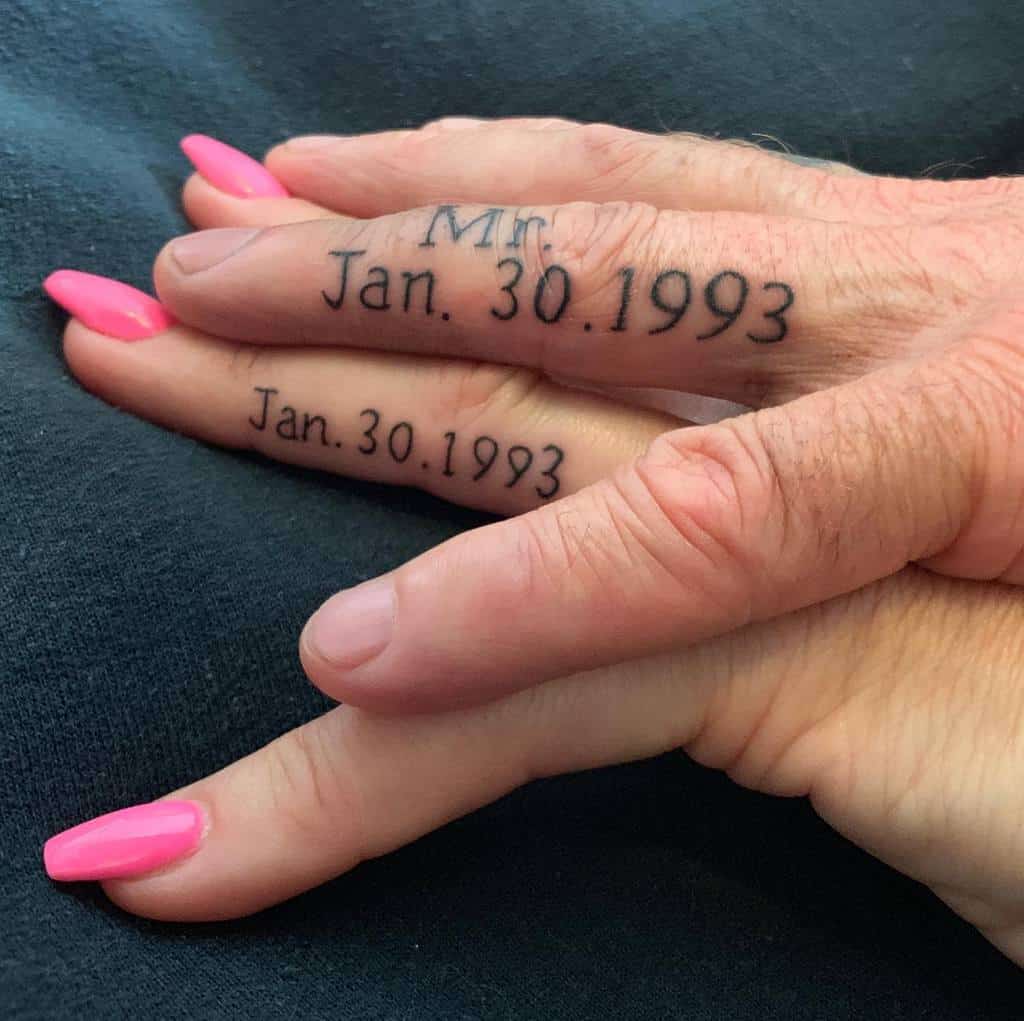 Matching wedding ring tattoos featuring the date "Jan. 30, 1993" and the title "Mr." on one hand, symbolizing a significant date in their lives