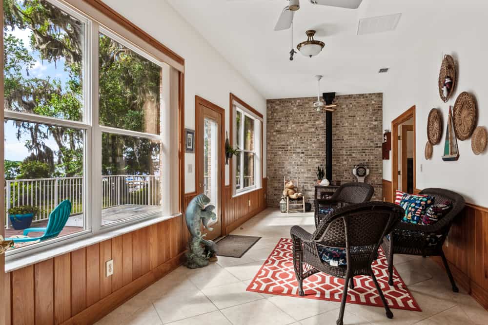 large enclosed room tile floor brick wall fireplace wicker furniture ceiling fan outdoor deck 