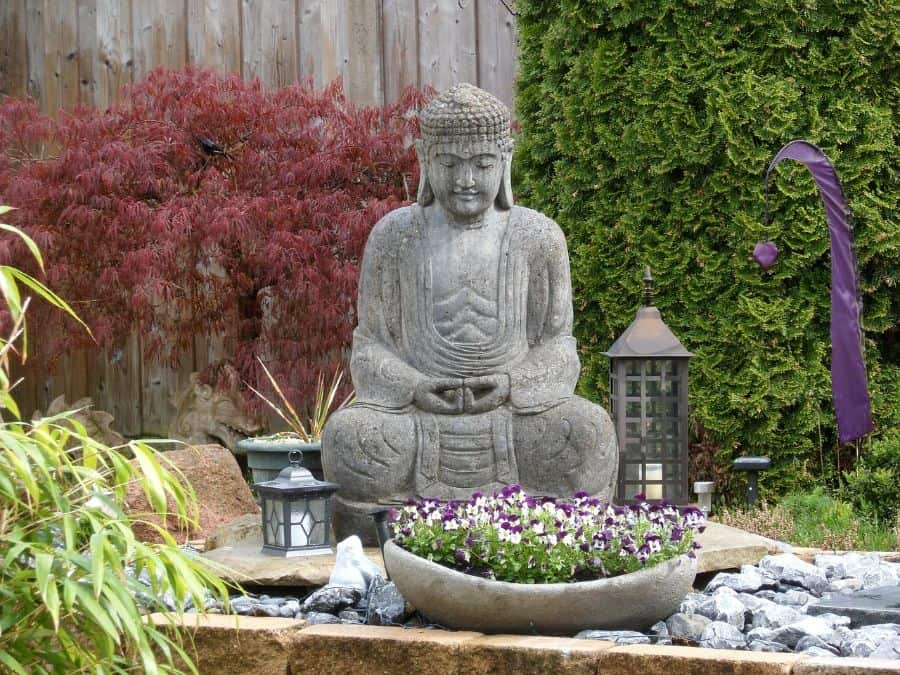 meditating stone statue in backyard lanterns with candles 