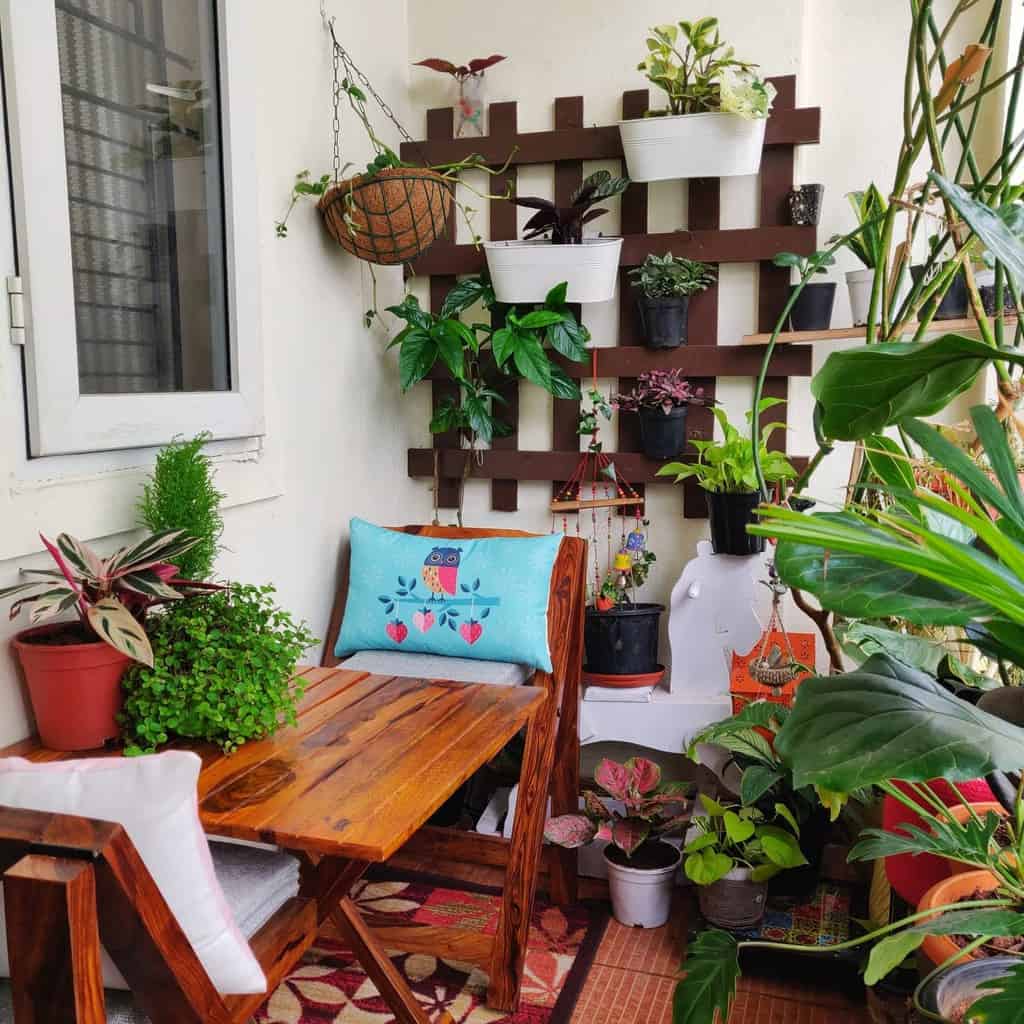 Small cozy patio with wooden furniture, vibrant potted plants, and a vertical garden.