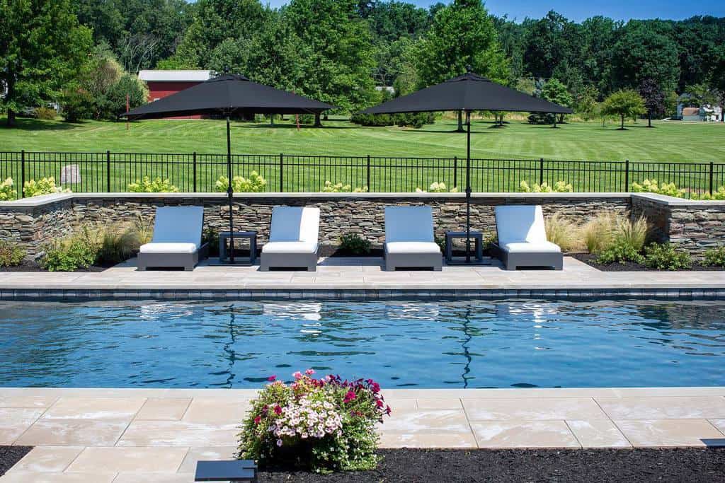 pool patio sun loungers black umbrellas stone retaining wall
