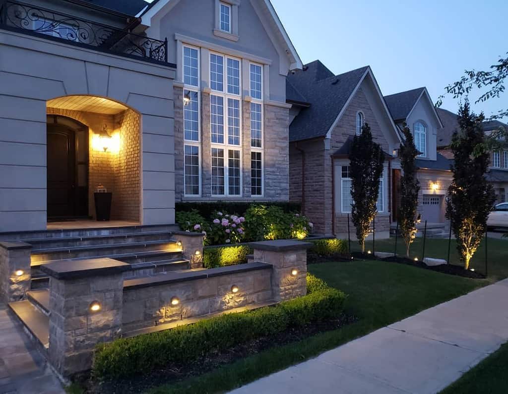 front yard stone wall shrubs garden sconces lights