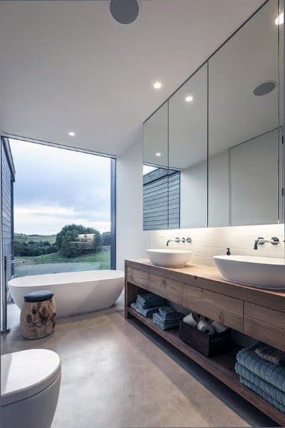 Modern bathroom with seamless medicine cabinet mirror, freestanding tub, and wooden vanity