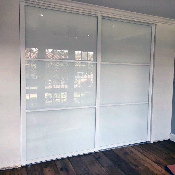 Frosted glass sliding closet doors enhance the room's wooden floors