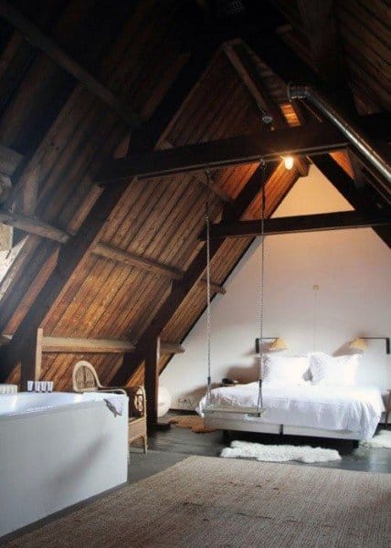 Charming attic bedroom with wooden beams, a swing bed, and a rustic bathtub