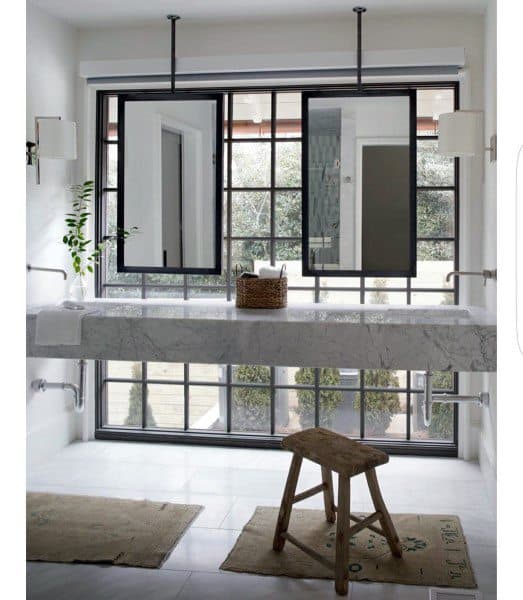 Modern bathroom with ceiling-mounted mirrors, marble floating vanity, and large window.