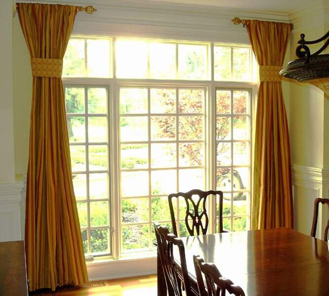 Traditional dining room with gold striped curtains, decorative curtain rods, and a wooden dining set.