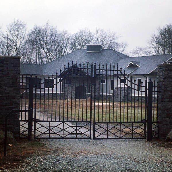 Decorative black metal driveway gate with spiked finials and arched top design.