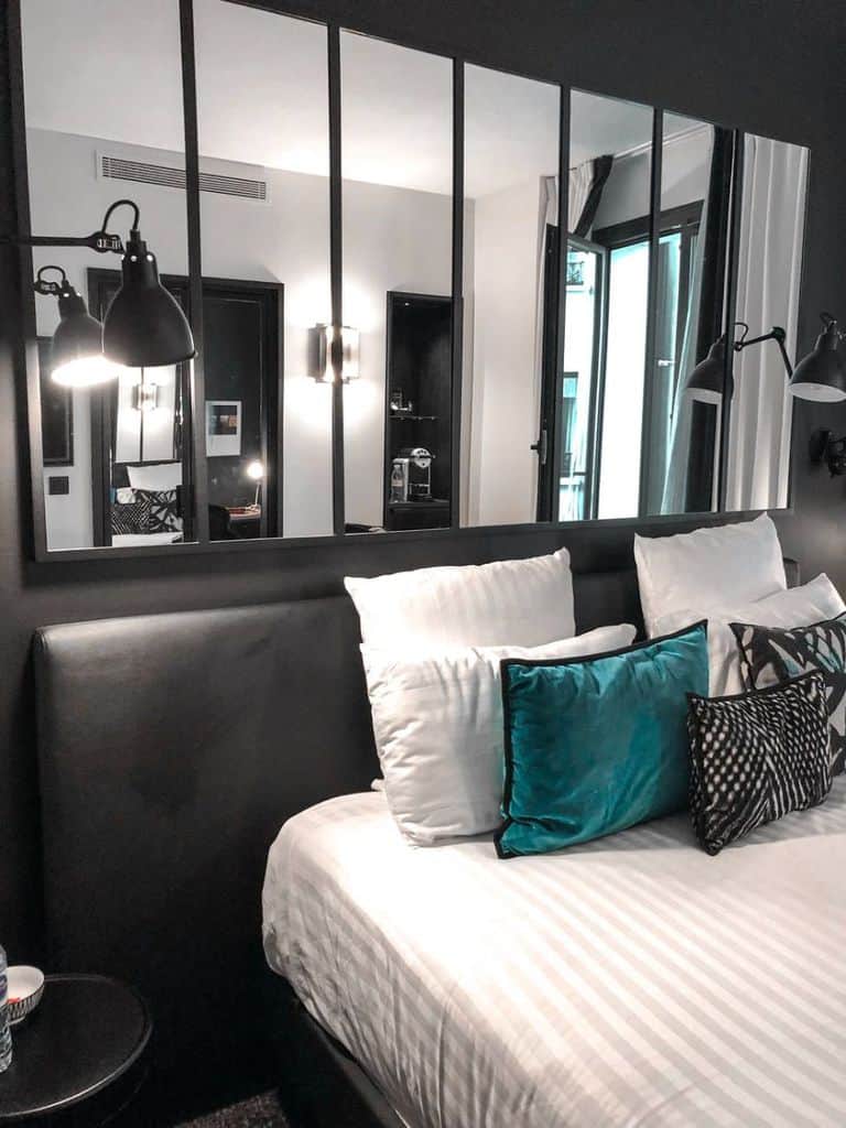 Modern bedroom with large mirrored panels above the bed and teal accent pillows.