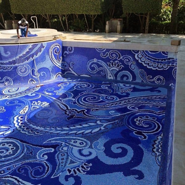 Intricate blue mosaic pool tiles with paisley-inspired decorative patterns on floor and walls.