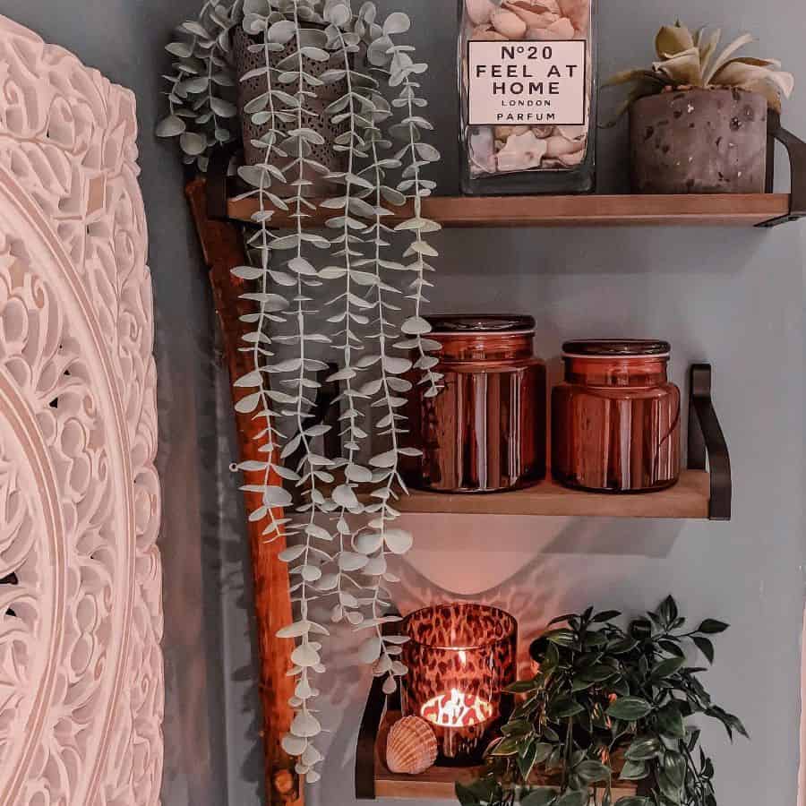 Decorative bathroom shelves with plants, candles, and fragrance jar.