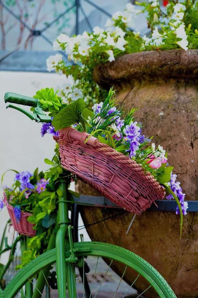 green painted bicycle with pink wicker baskets holding flowers