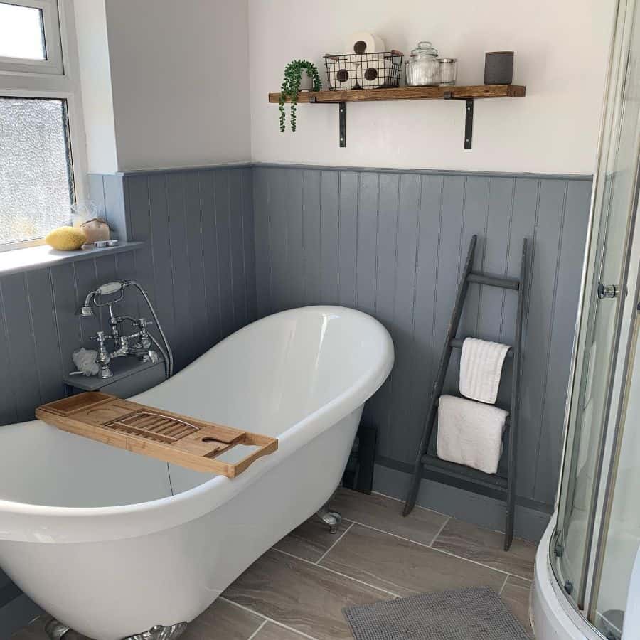 Small country-style bathroom with freestanding bathtub, towel ladder, and wooden shelf.