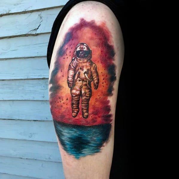 Colorful Deja Entendu-inspired tattoo featuring a floating astronaut over a sunset ocean with a vivid red and blue sky.