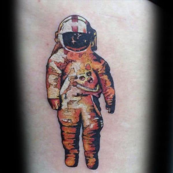 Bold Deja Entendu astronaut tattoo with a graphic, comic-style design and warm orange shading on a light skin background.