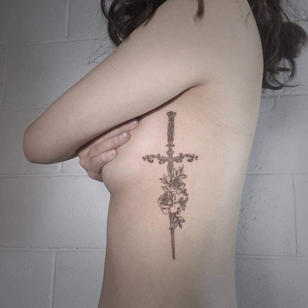Elegant black ink tattoo of an ornate sword adorned with roses, blending strength and beauty in fine-line detail