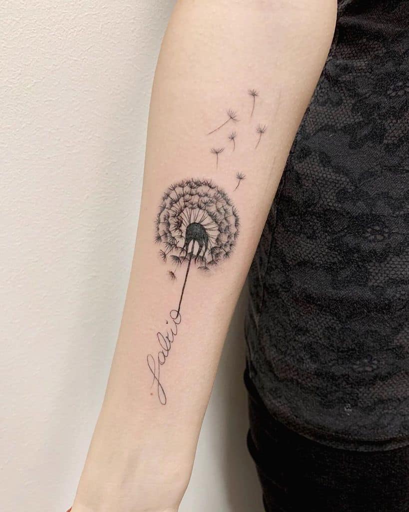 A black and white tattoo of a dandelion with seeds floating away, accompanied by the word "falling" in cursive below the flower.