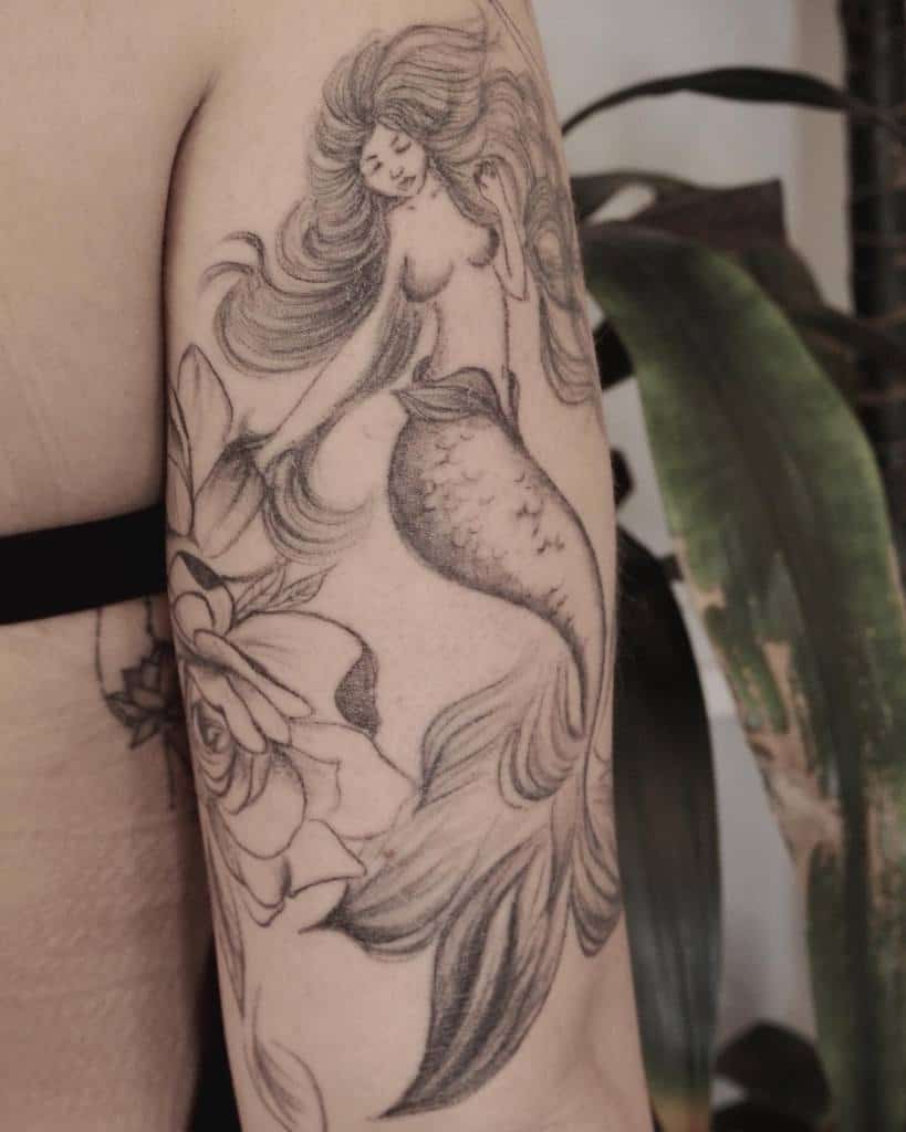 Tattoo of a mermaid with flowing hair and a flower