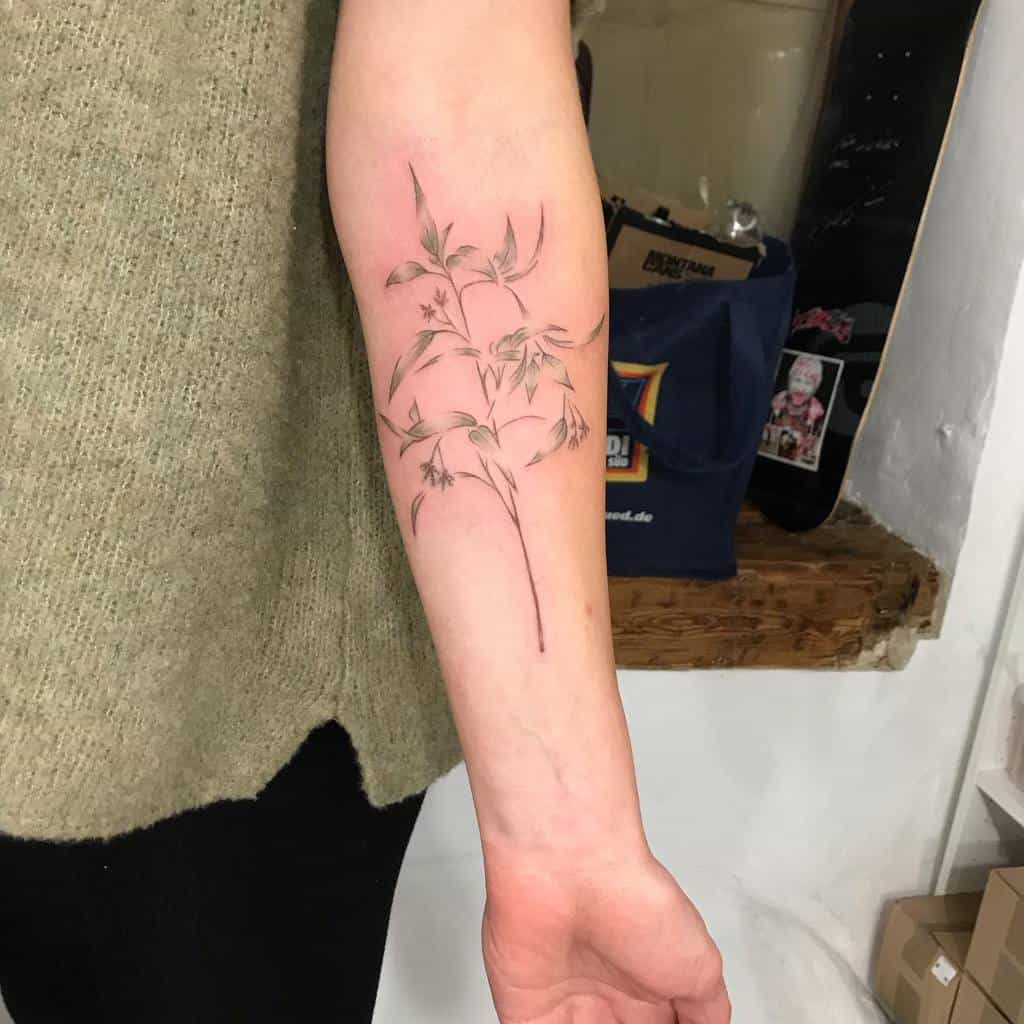 Delicate fine-line botanical tattoo of a slender floral branch with leaves and tiny blossoms, placed elegantly