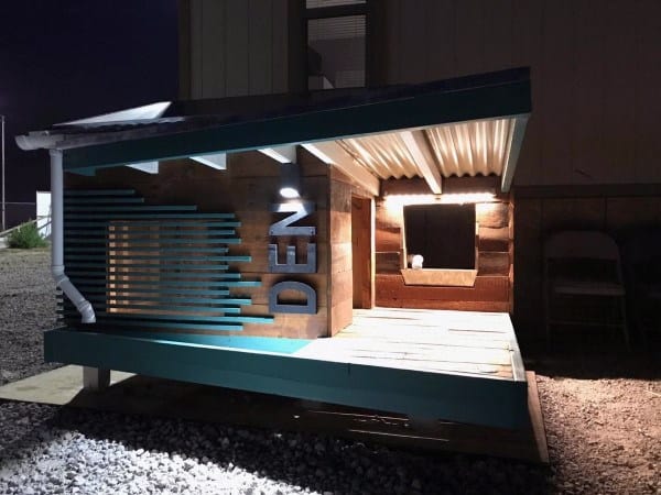 Modern dog house with slanted roof, "DEN" sign, and a cozy lit interior, perfect for your dog's comfort