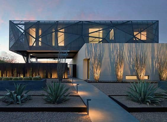 Modern desert home with agave plants, gravel landscaping, and dramatic architectural lighting.