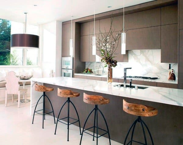 Contemporary kitchen with marble backsplash, brown cabinets, and wooden bar stools at island.