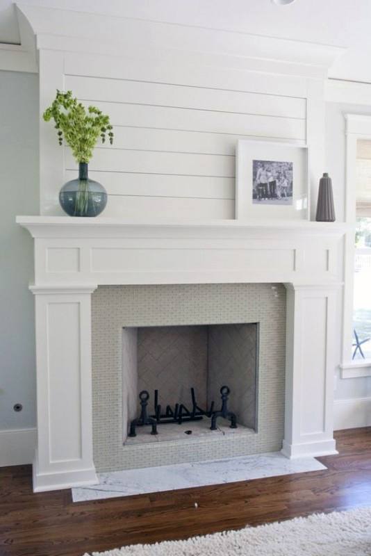 This fireplace features a white mantel, herringbone tile, and a marble hearth.