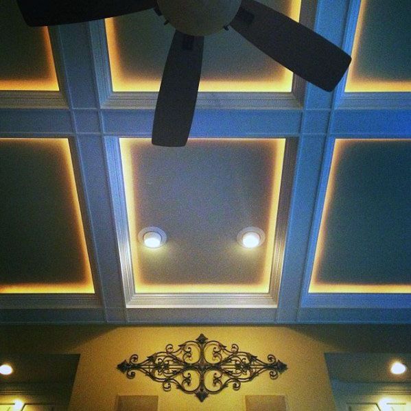 Stylish coffered ceiling with crown molding lighting and a ceiling fan, adding warmth to the room