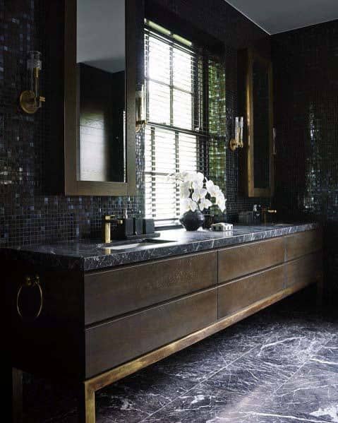 Luxurious black bathroom with marble countertop, dark mosaic tiles, and gold accents.