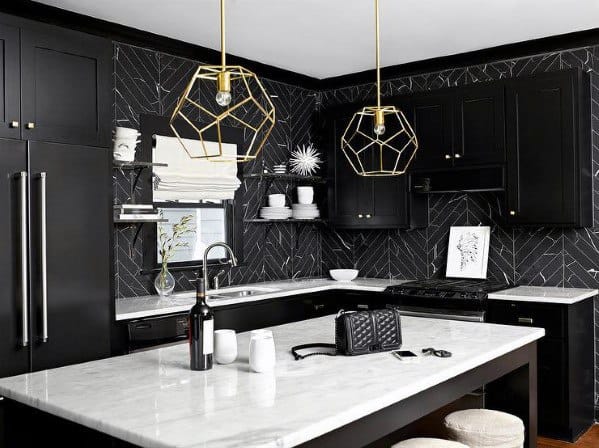 Black kitchen cabinets with marble countertops, geometric gold pendant lights, and patterned backsplash.