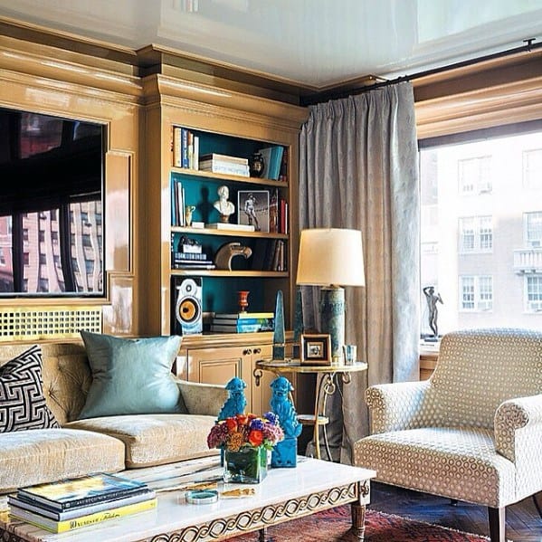 Chic living room with built-in bookcase, teal accents, cozy seating, patterned chair, and vibrant decor pieces
