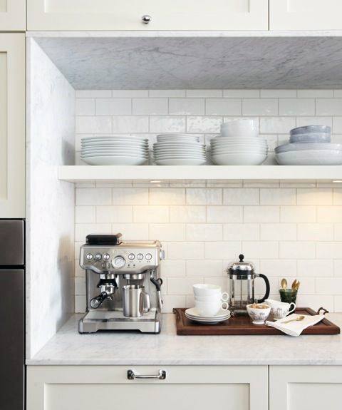 Coffee bar with marble countertop, white backsplash, shelves, coffee machine, and French press.