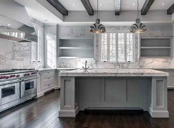 Modern grey kitchen with marble island, pendant lights, and dark wood flooring.