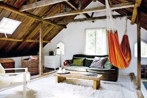 Colorful hammock in a rustic attic living space with wooden beams and cozy seating.
