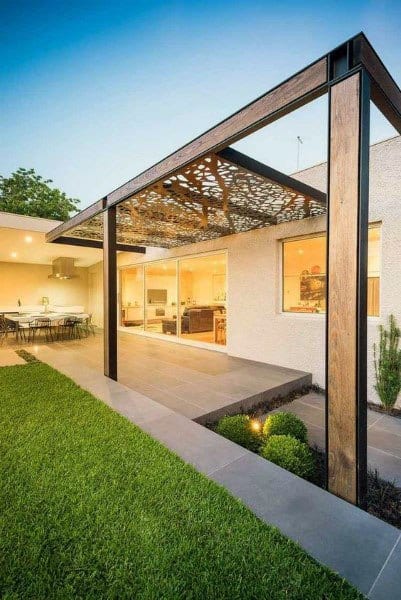 Modern pergola with laser-cut metal roof, wood and steel frame, overlooking a lush backyard lawn.