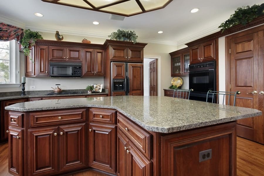 Spacious kitchen with wooden cabinets, granite countertops, island, and built-in appliances under recessed lighting