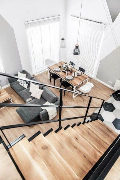 Scandinavian loft with wood flooring, modern dining area, and black metal staircase railing.