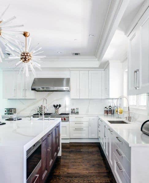White kitchen with marble countertops, dark wood island, and modern starburst lighting.