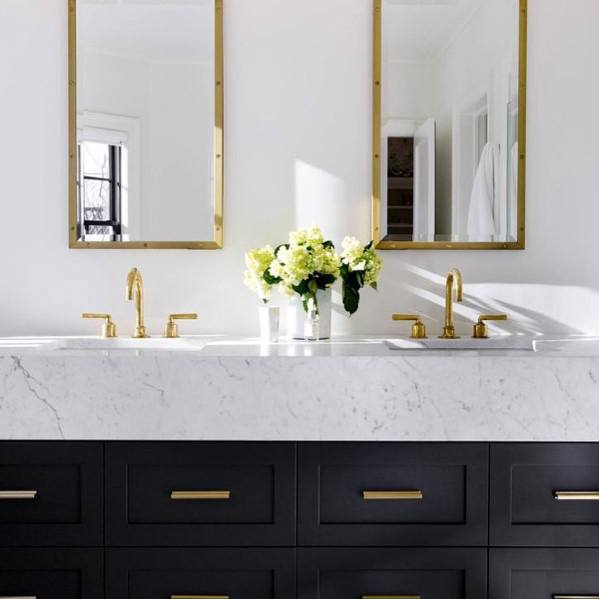 Black vanity with marble countertop, gold fixtures, and twin mirrors.