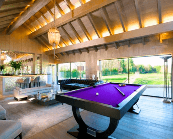 Modern billiard room with vaulted ceiling, purple felt table, and large glass windows.