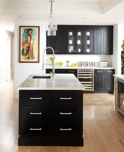 Black kitchen cabinets with light hardwood floors, glass cabinet doors, and a central island.