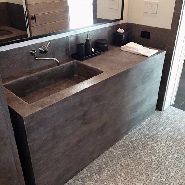 Modern bathroom with concrete sink and counter, mosaic tile floor, and toiletries
