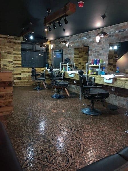 Industrial-style barbershop with penny tile floor, custom logo design, and rustic wooden accents.